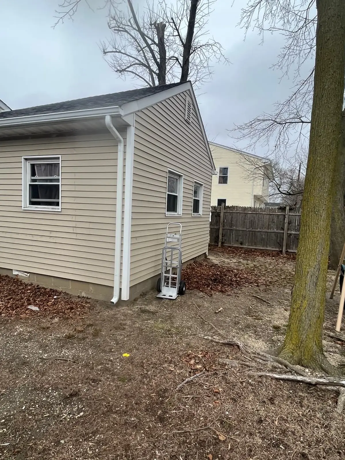 Selling in the Amityville housing market: back corner of a tan ranch under bare trees