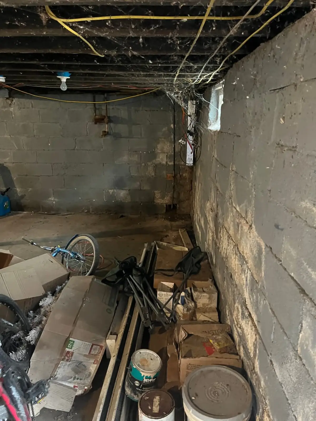 Selling a house with tenants in it in Amityville: cinder block basement with boxes and old bikes
