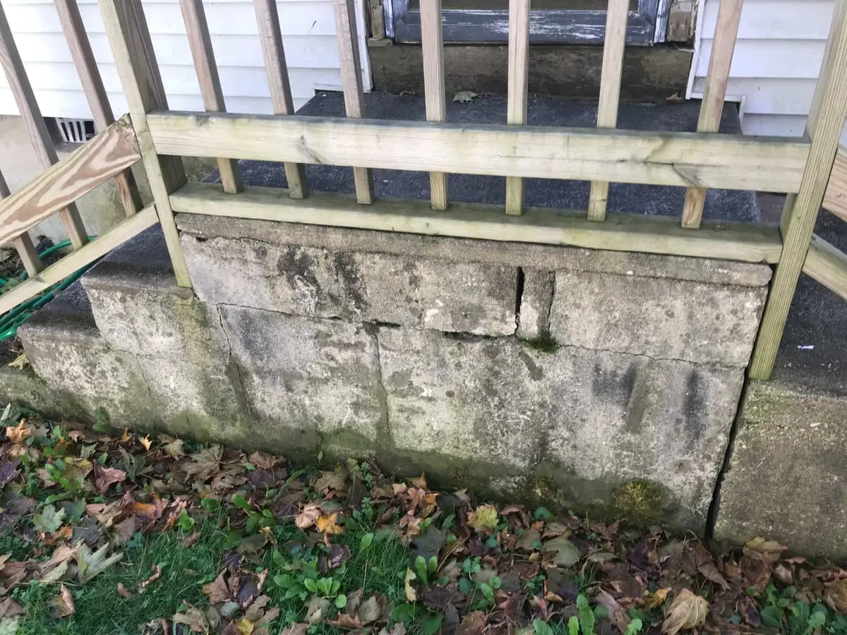Selling a house as-is in Amityville: cracked concrete block foundation under a back porch