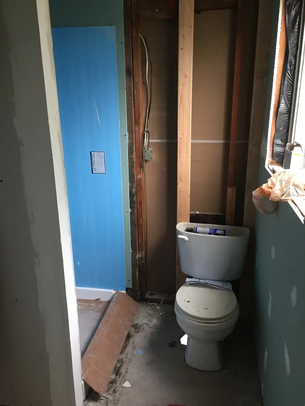Selling a house with unpermitted work in Amityville: gutted bathroom with open studs and an old toilet