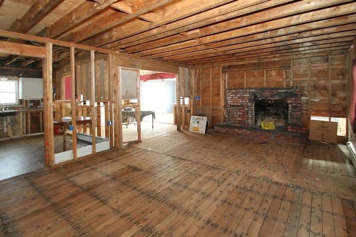 Selling a fire-damaged house in Amityville: living room opened to bare studs by a brick fireplace