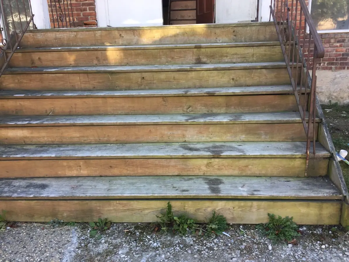 Selling a rental property in Amityville: weathered wooden front steps with weeds at the base